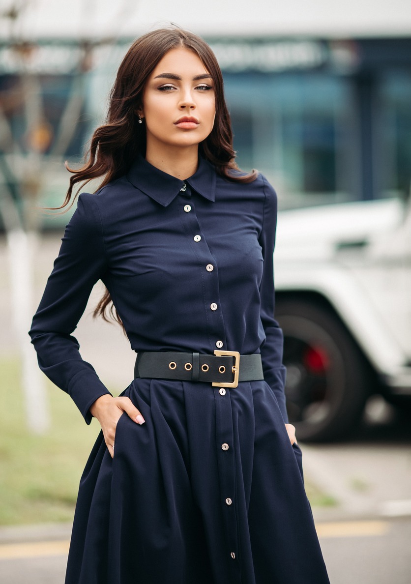 A woman in dark blue dress and black leather belt.