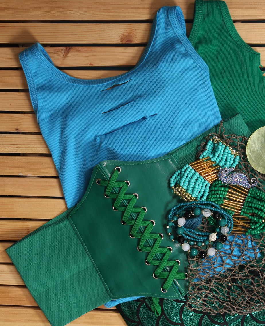 A green lace up belt on top of shirts with and accessories.