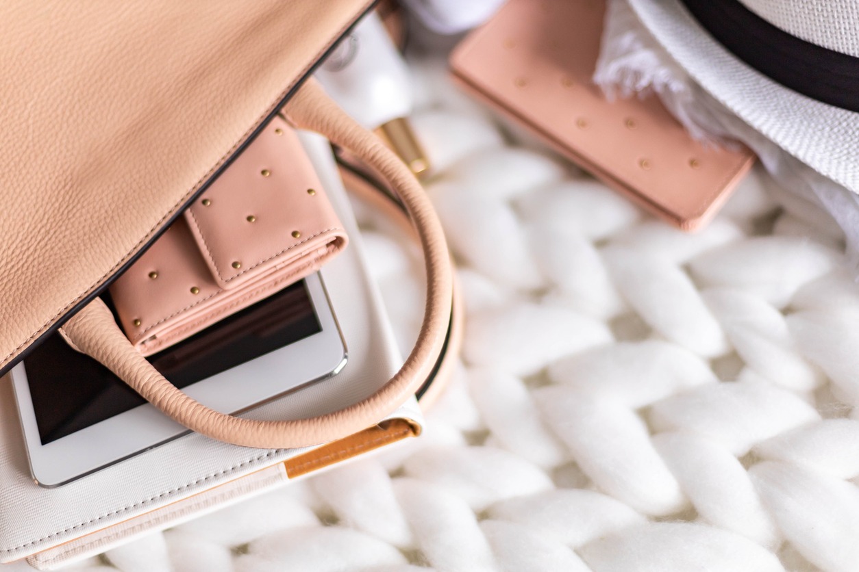 A blush pink handbag with contents peeking