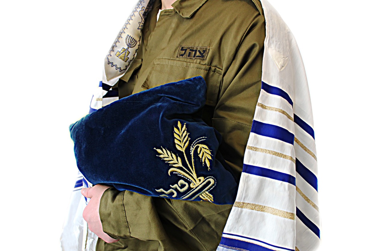 Religion in army of Israel. Religious soldier with a Tzitzit on his shoulders and bag Tallit on a white background (Hebrew translation on the bag - Tallit, on the uniform of a soldier - IDF