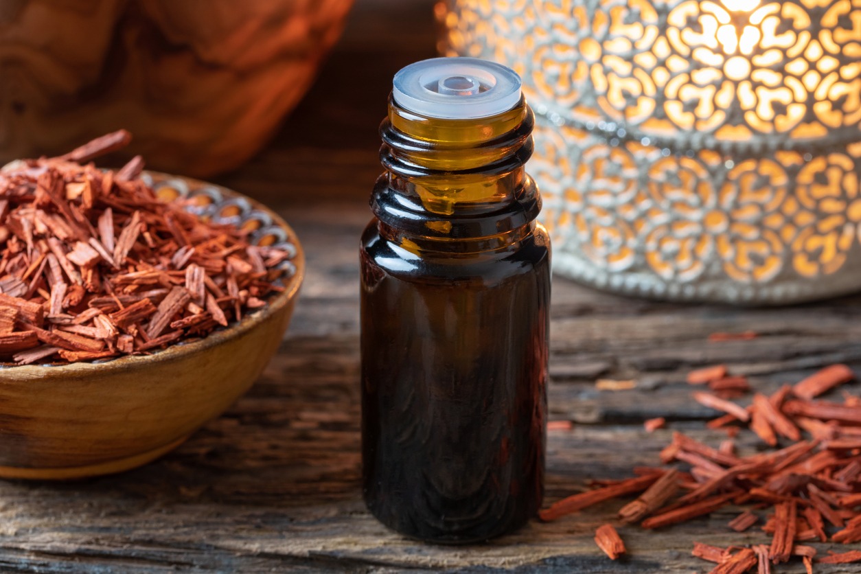 A bottle of sandalwood essential oil with red sandalwood chips