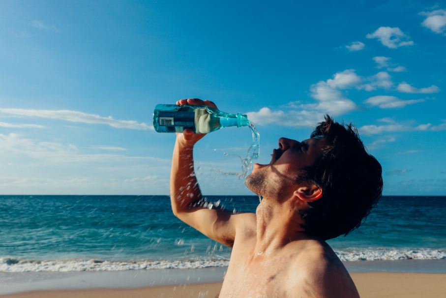 A man drinking bottled water by the beach
