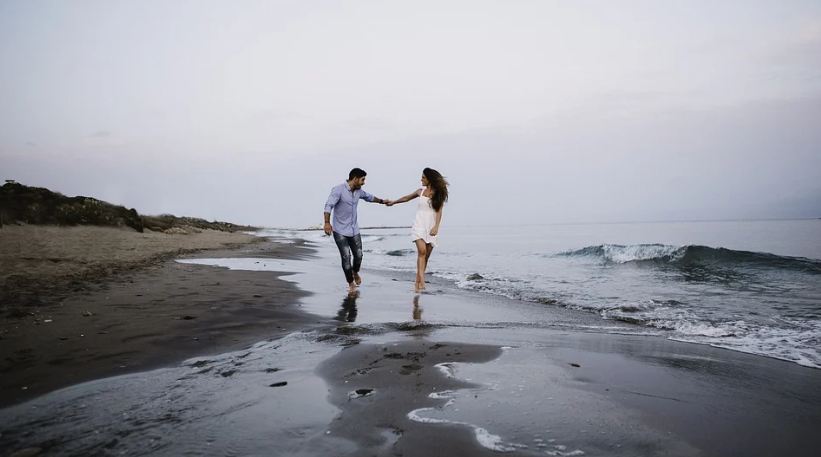 a couple strolling by the beach holding hands, sand, sea
