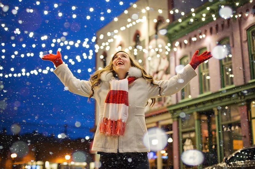 a smiling woman with scarf and gloves, Christmas lights, snow