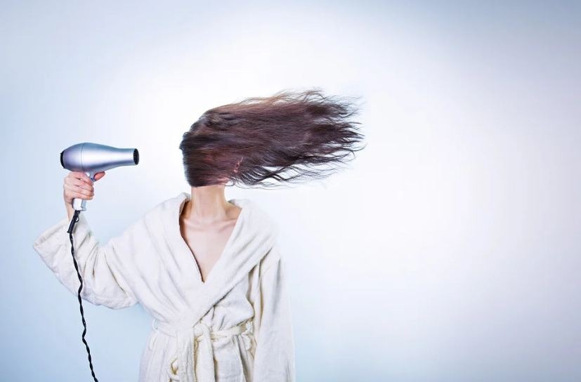 a woman drying her hair with a hairdryer