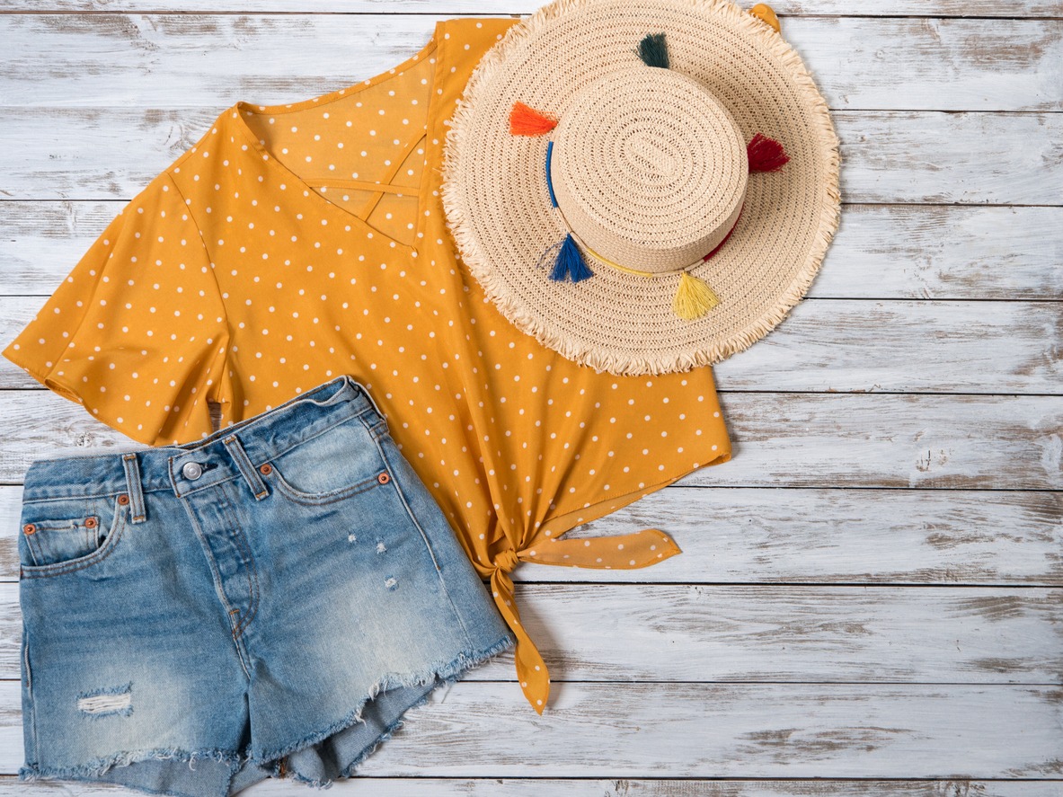 Womens clothing, accessories ( denim shorts, yellow blouse in polka dot, straw hat). Fashion outfit, spring summer collection. Shopping concept. Flat lay, view from above