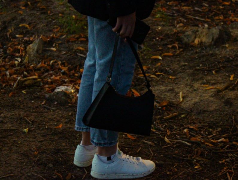 a person holding a handbag close to the ground