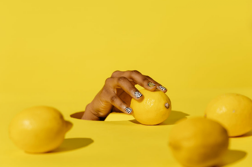 a person’s hand grabbing a lemon, lemons