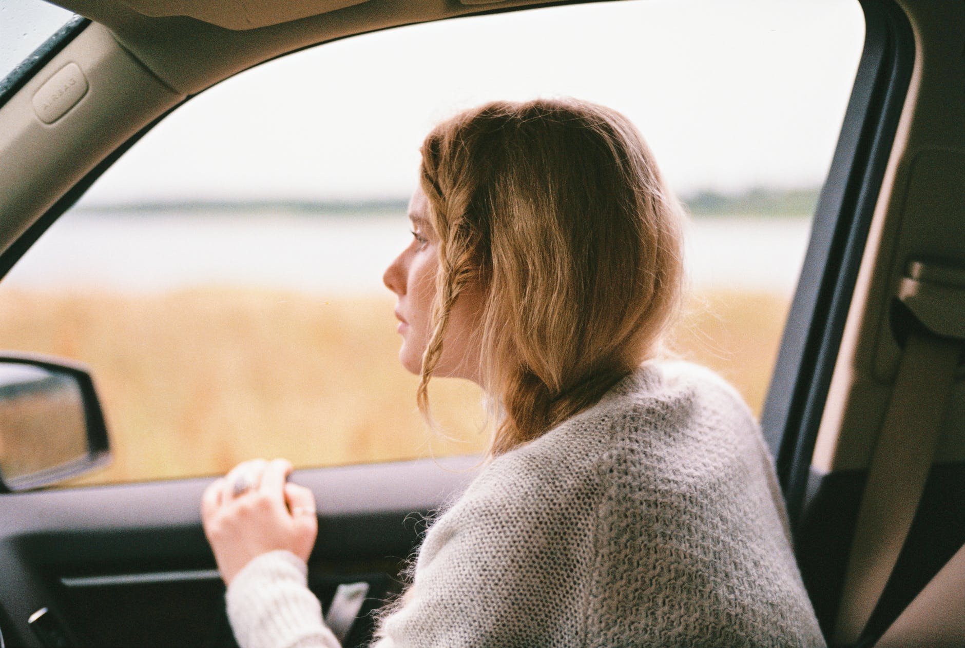 a woman inside a car wearing a sweater