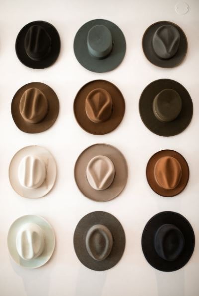 assorted fedora hats hanging on the wall