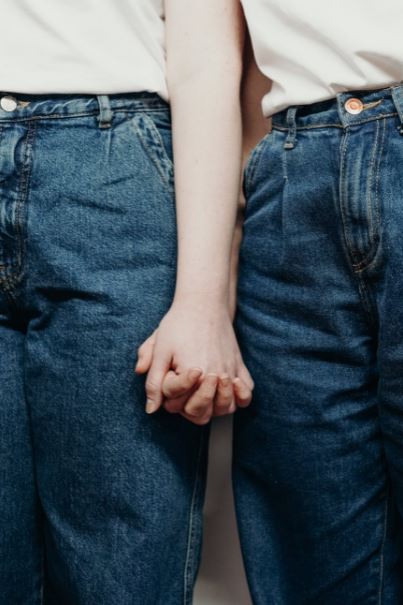 two people wearing denim jeans side by side and holding hands