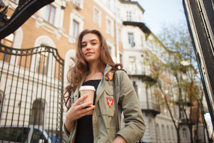 Youth pretty female with coffee on street