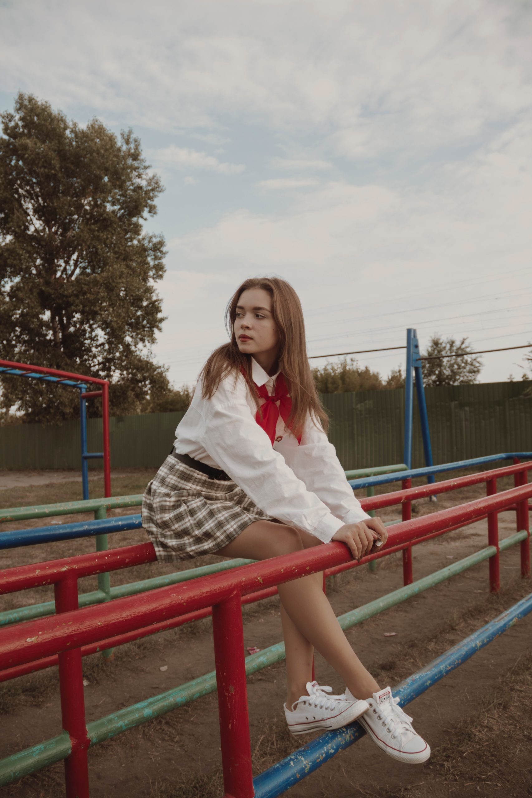 a girl wearing a mini skirt sitting on a metal railing