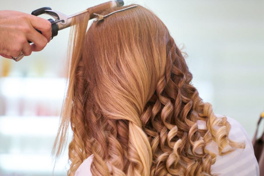 a hairstylist curling a woman’s hair