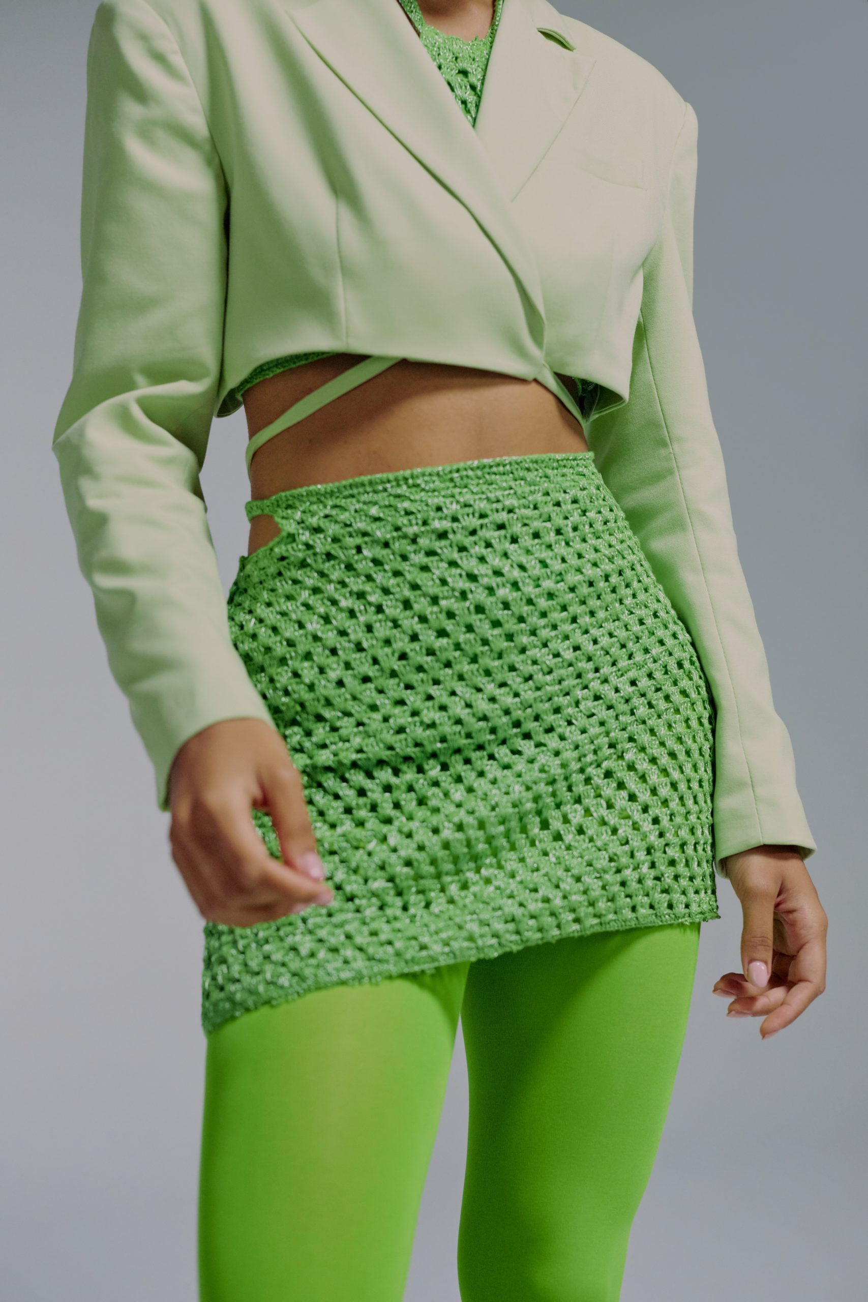 a headless picture of a woman wearing a green mini skirt above leggings