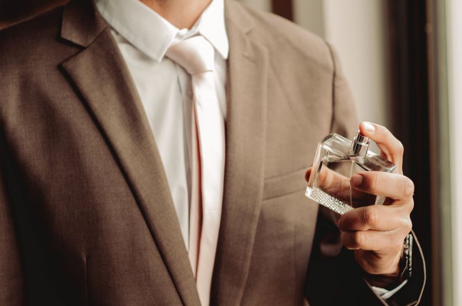 a man wearing a suit and tie spritzing perfume