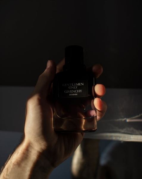 a man’s hand holding a perfume bottle