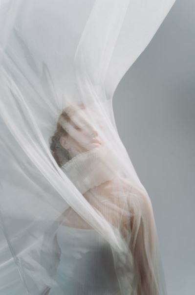 a woman covered by a white chiffon fabric