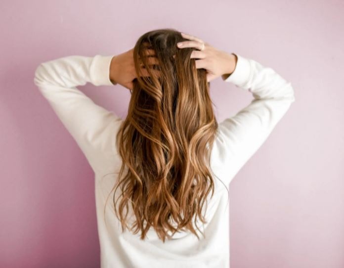 a woman facing the wall while holding her hair