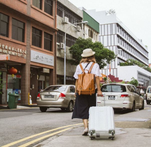 a woman walking down the street pulling her luggage along