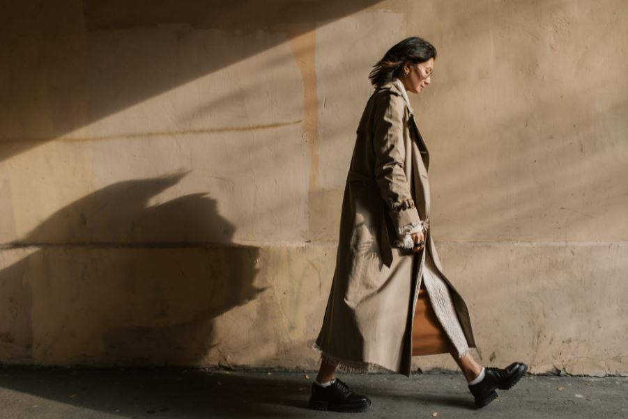 a woman wearing a full-length trench coat walking