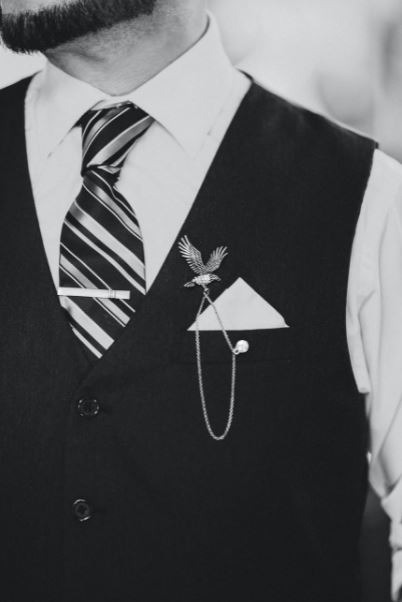 the torso of a man wearing an eagle-shaped lapel pin with a chain
