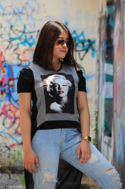 a woman wearing a graphic tee and ripped jeans