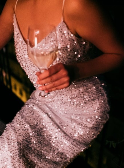 a woman wearing a sequined dress holding a glass of alcohol