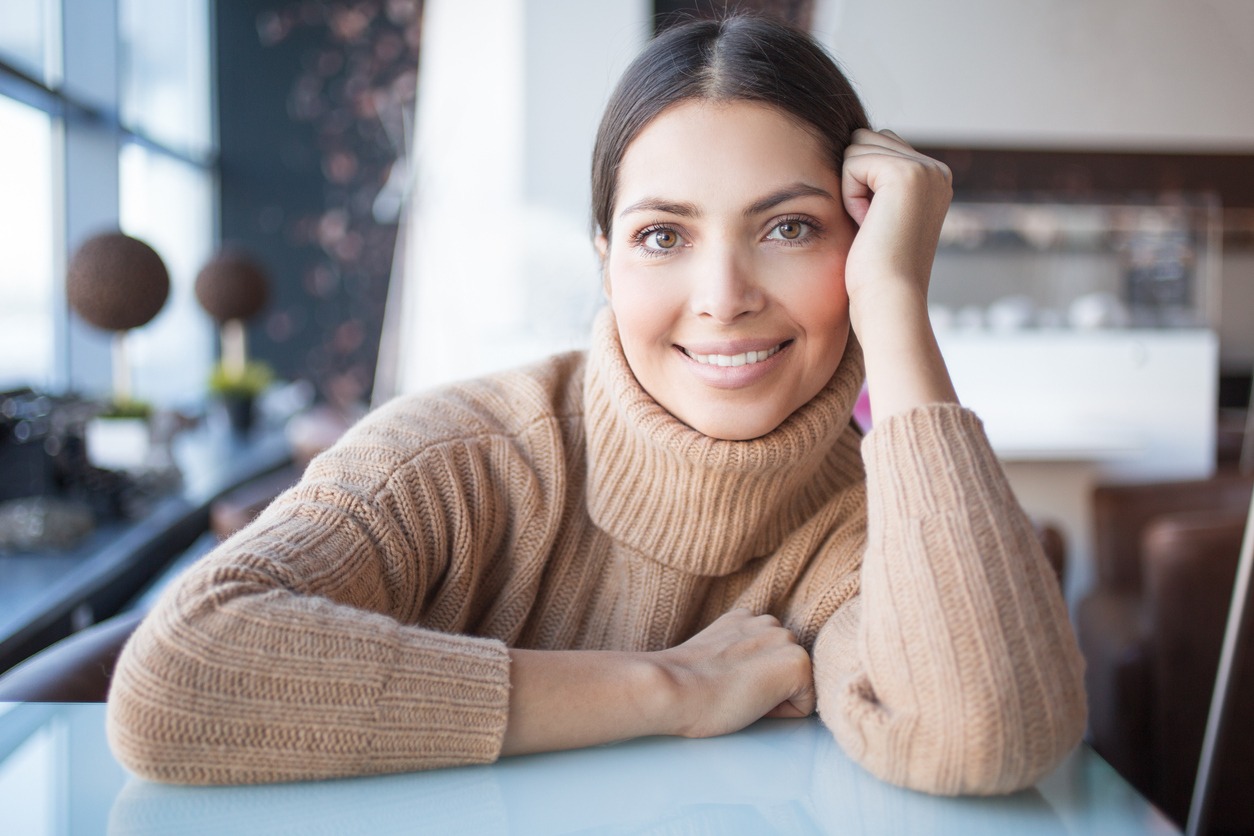 Smiling woman in sweater leaning on hand