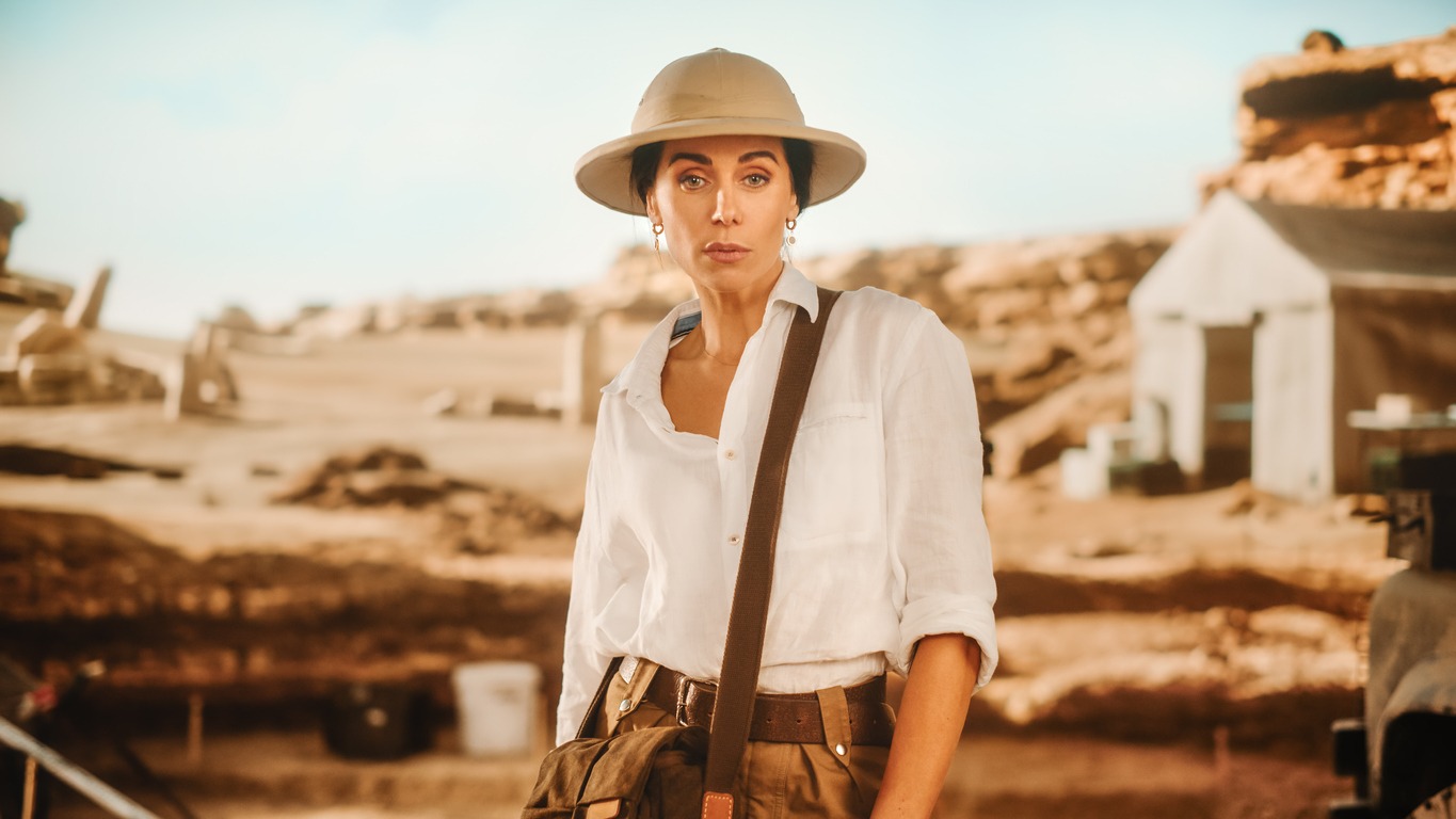 Portrait of Beautiful Female Adventurer Posing and Looking at Camera. Stylish Great Archaeologist Standing with Ancient Civilization, Fossil Remains Archeological Site, Forgotten City in Background