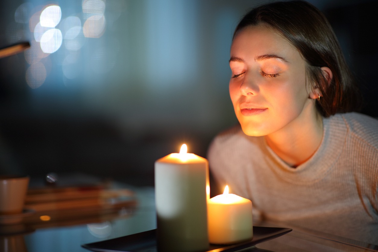 Woman smelling lighted candle