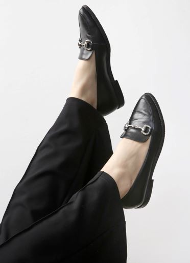 a close up of the feet of a woman wearing black leather handmade loafers