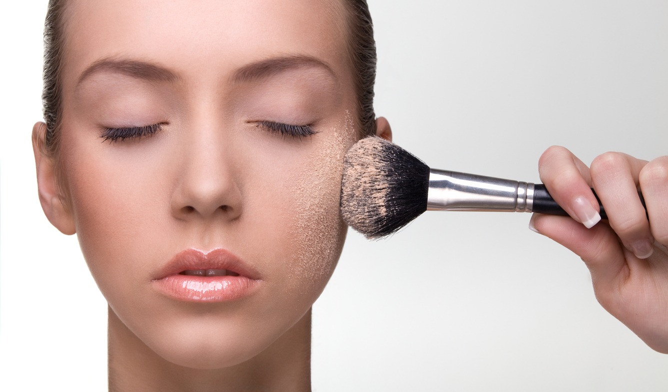 A woman applying make-up powder on the cheek