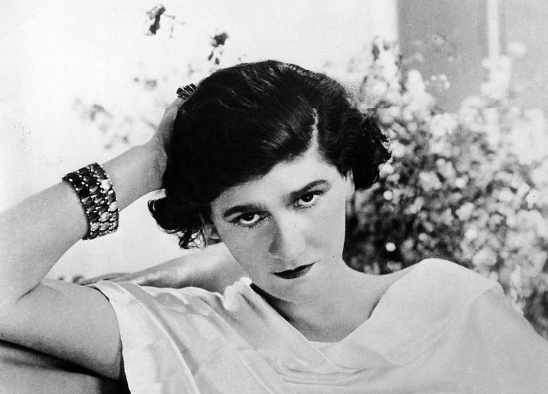 Gabrielle "Coco" Chanel leaning on her hand set on a sofa