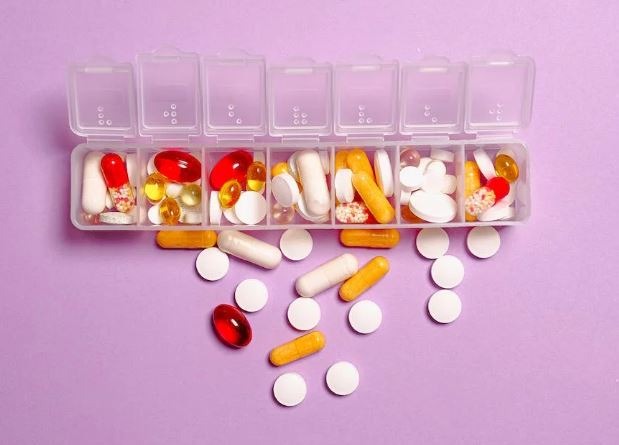 Medication capsules inside and outside a plastic medicine box 