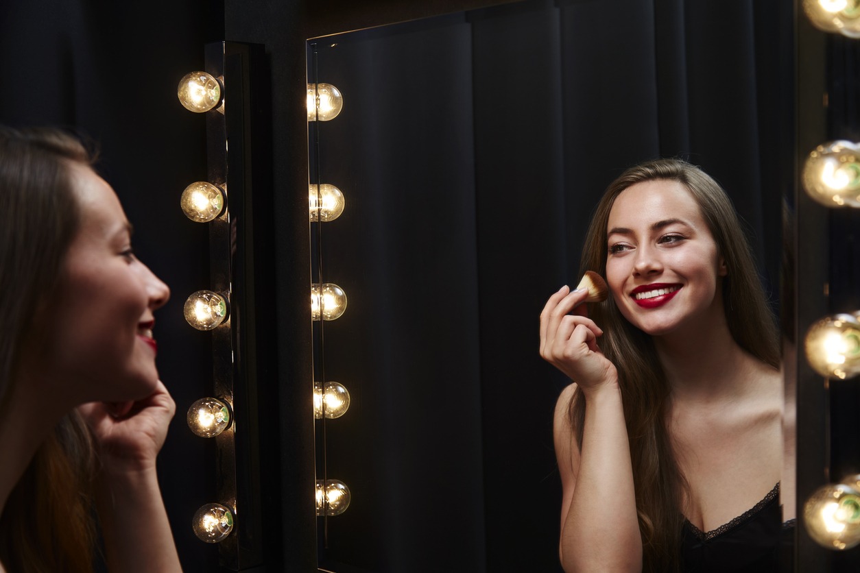 Woman applying make up  using a well lighted mirror