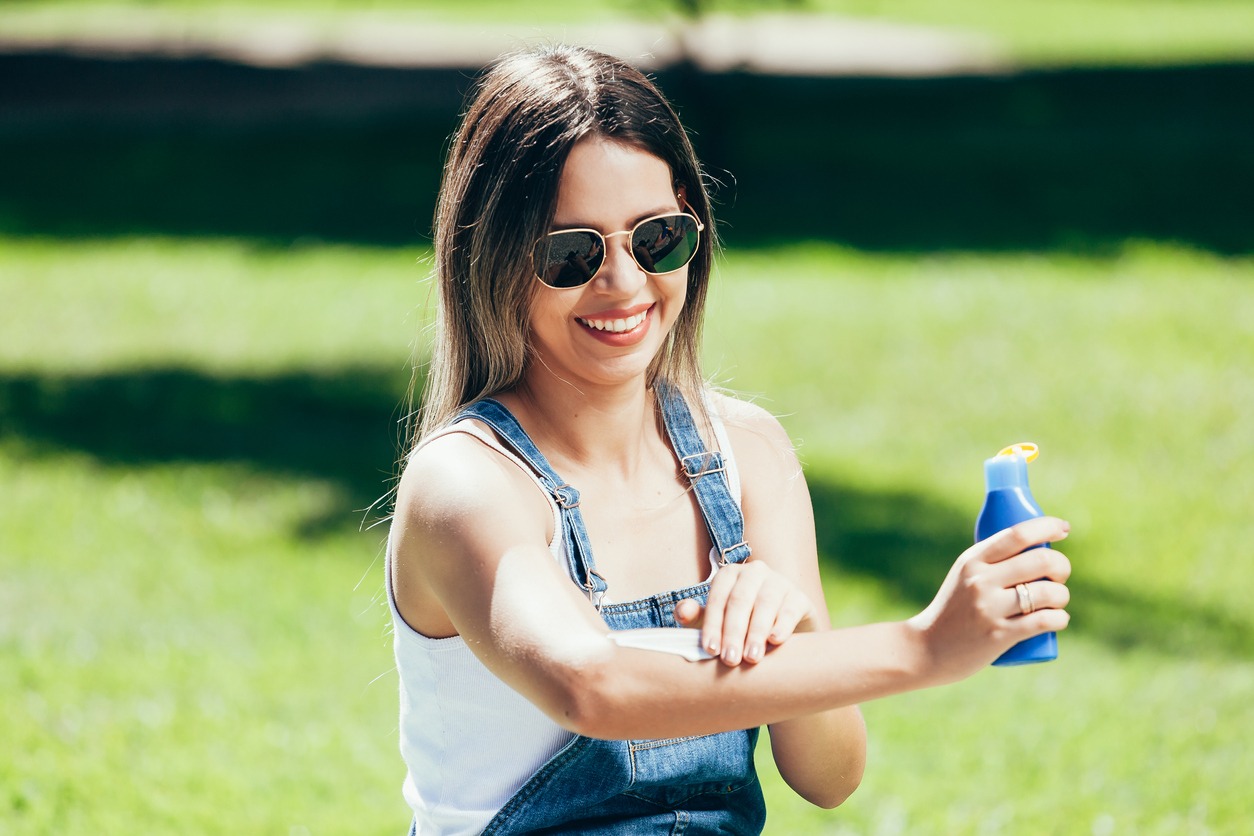 Young woman with sunscreen and sunglasses outside on a beautiful summer day