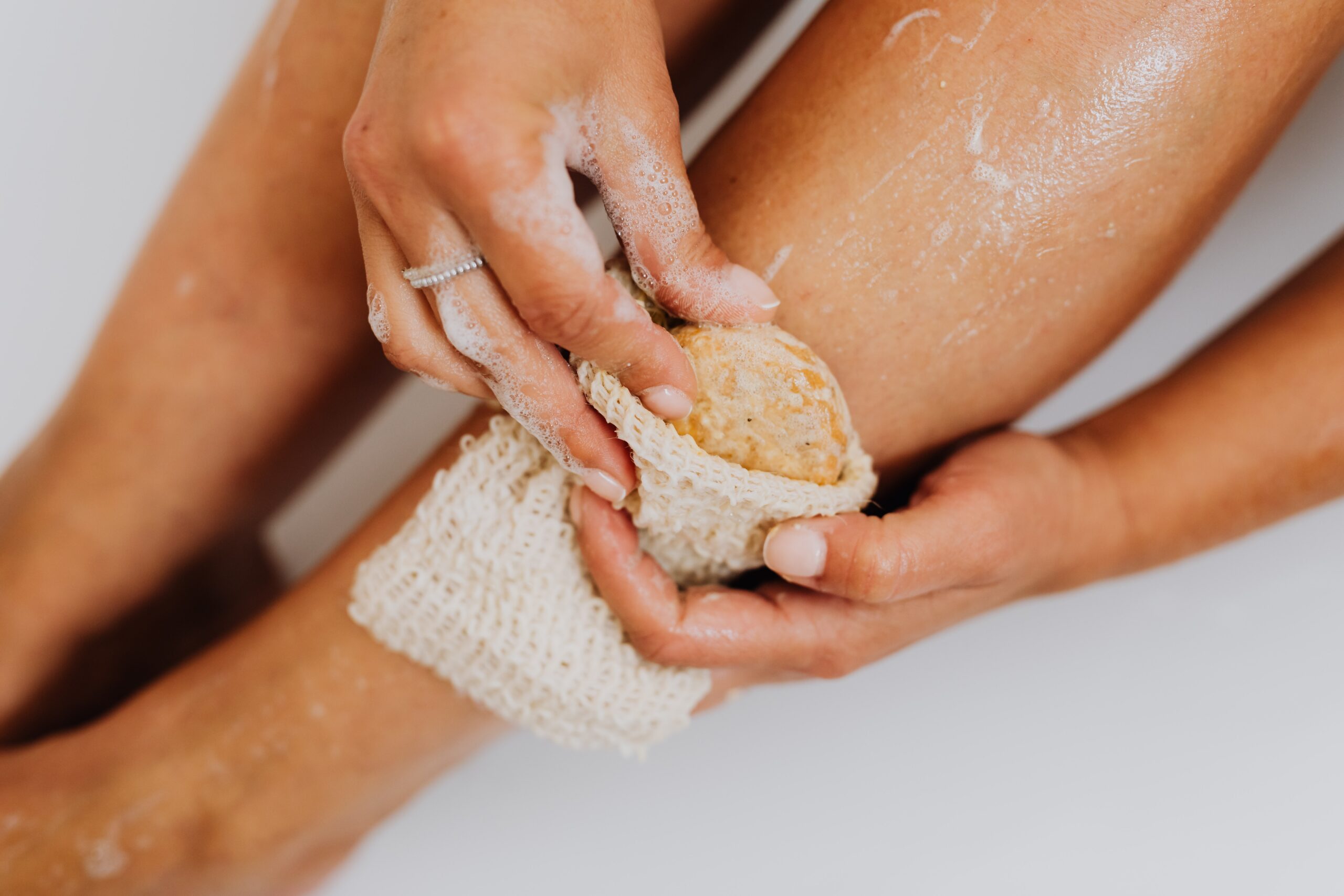 a person using a body scrub with soap on her leg