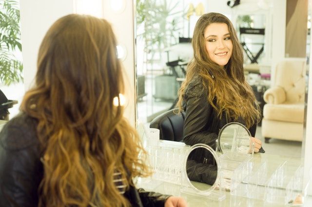 woman-looking-at-the-mirror-in-her-well-lighted-makeup-studio