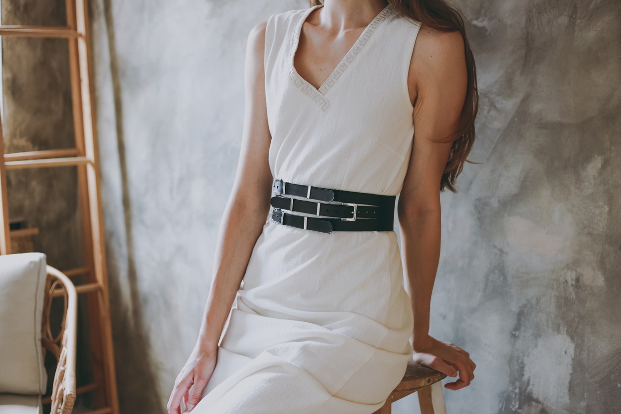 A  girl in a white dress with black leather belt.