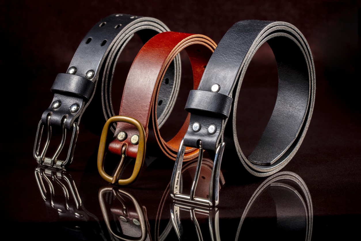 A group of multi-colored leather belts on a black background