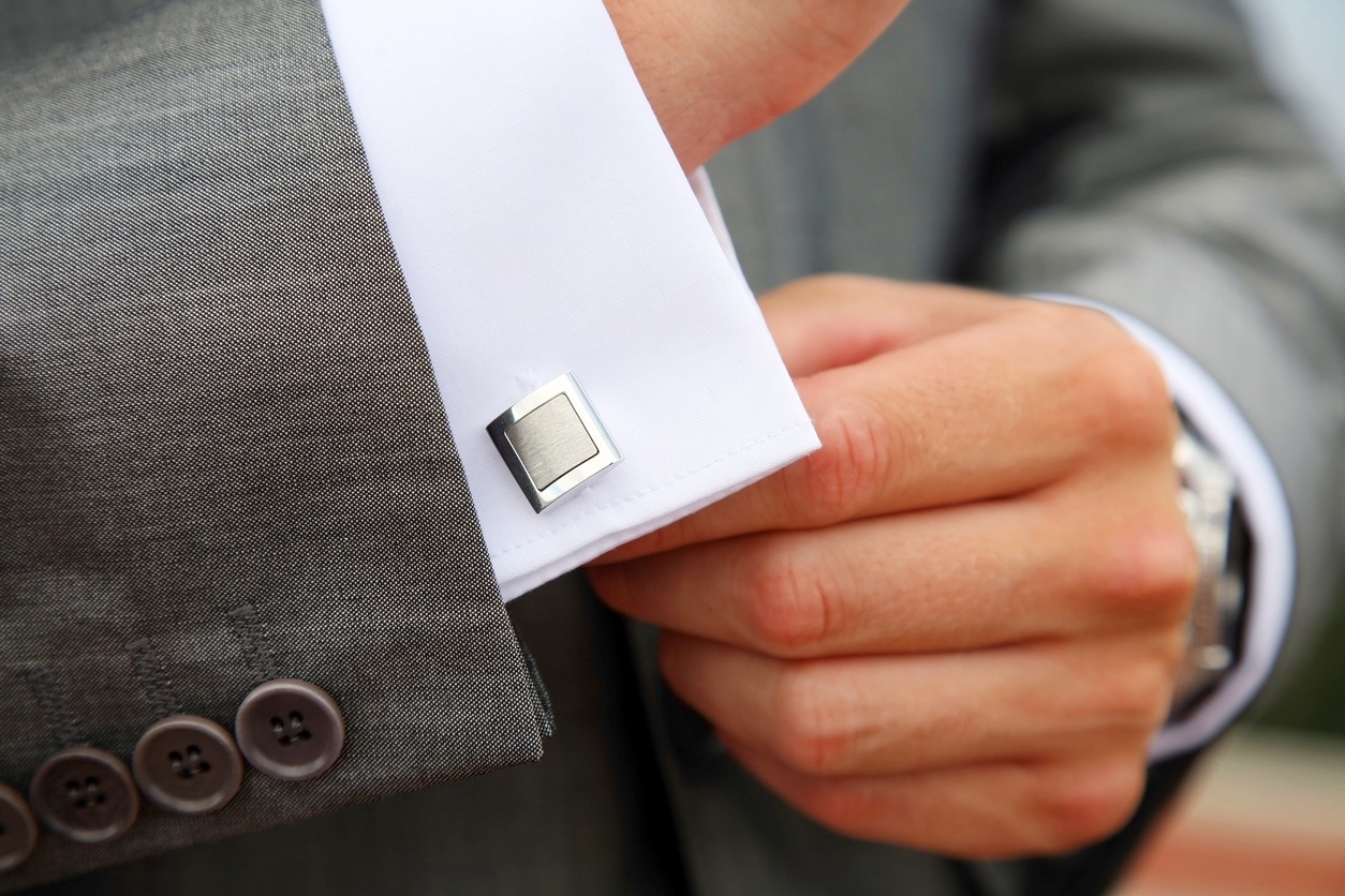 A man fastening a cuff-link before getting married