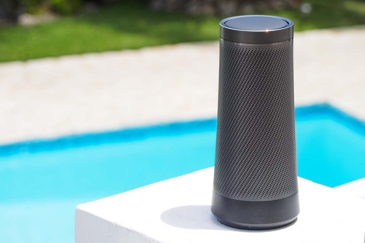 A modern portable music speaker by the swimming pool.