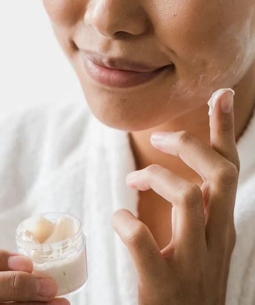 A person applying facial cream on her face