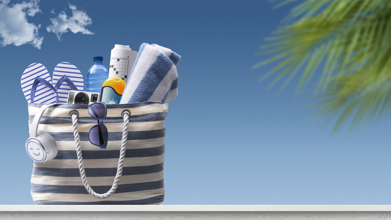 A striped white and navy beach bag filled with beach essentials