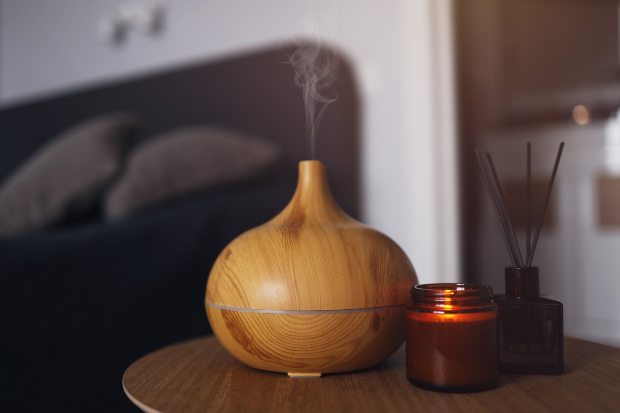 Aroma oil diffuser, air freshener and candle on a wooden table in the bedroom