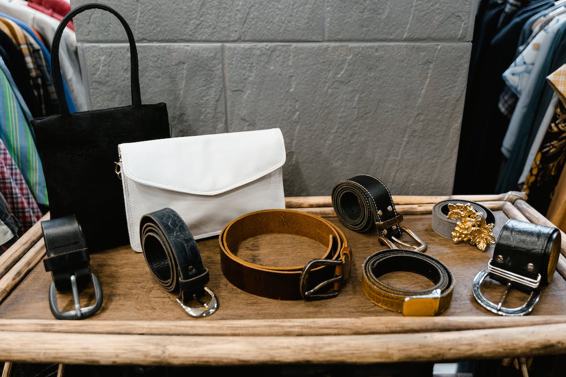 Assorted black leather belts on brown wood table