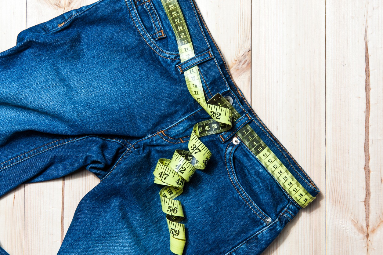 Blue jeans and a tape measure on a wooden background
