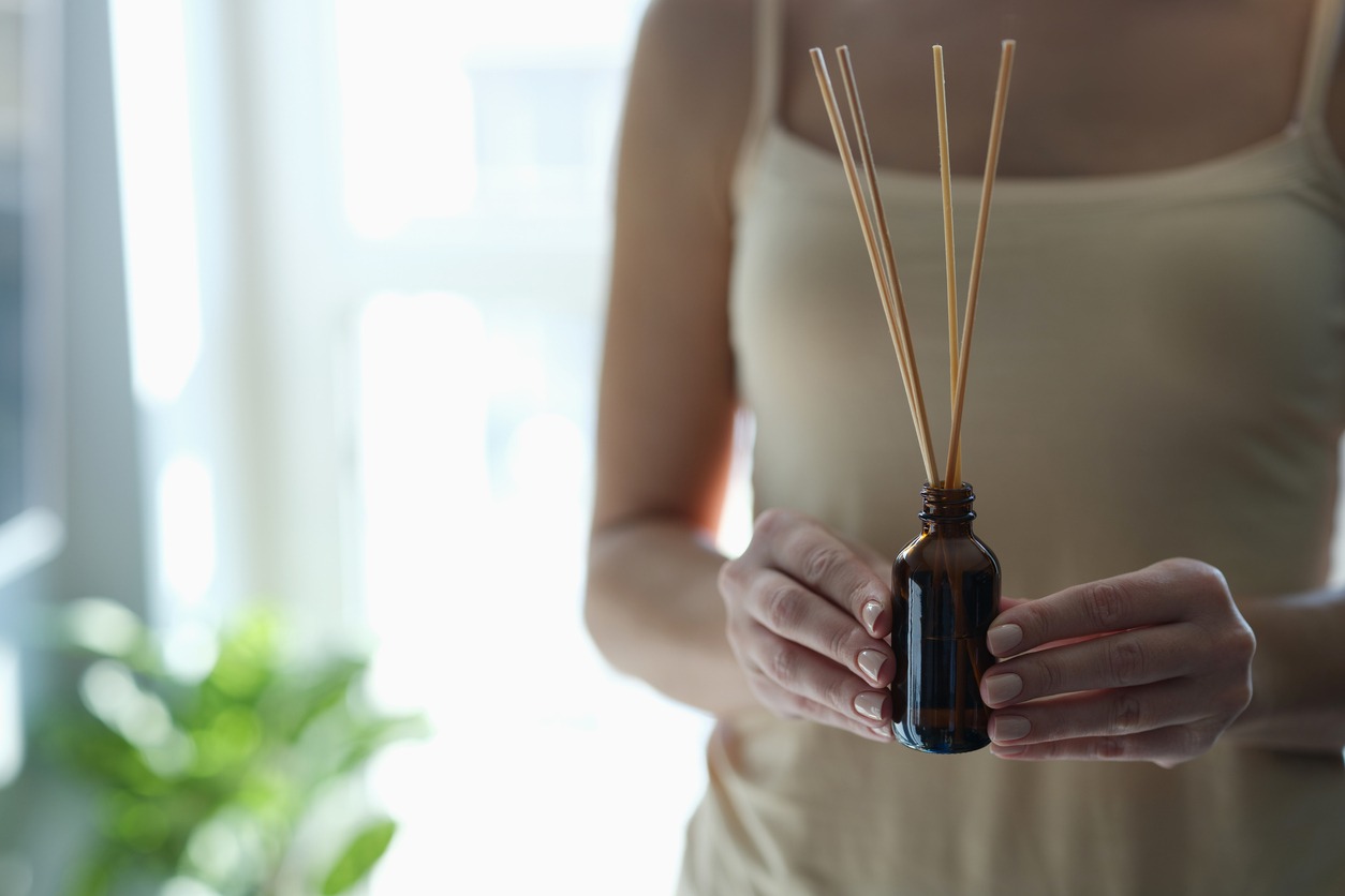 Bottle with incense sticks in female hands closeup