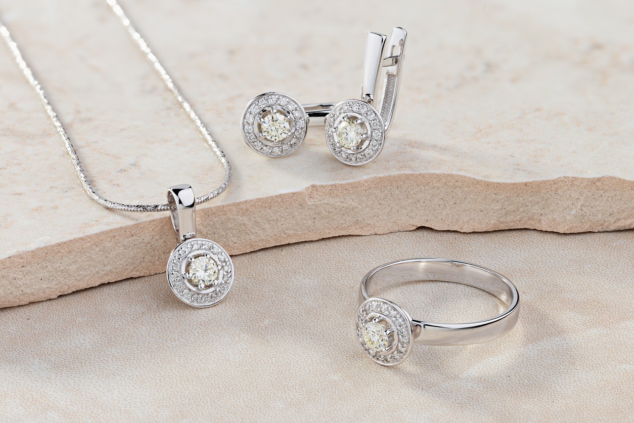Elegant jewelry set of a white gold ring, necklace, and earrings with diamonds. Silver jewelry set with gemstones. Product still life concept